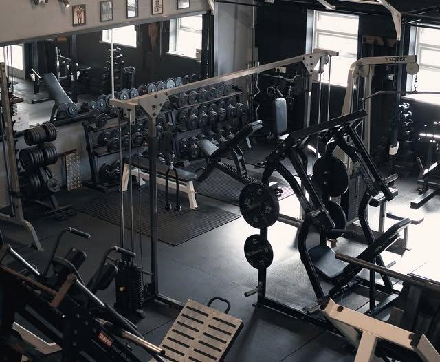 The gym floor on a sunny afternoon, racks and plate-loaded machines